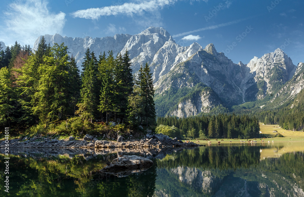 Scenic image of Fairytale lake Fusine during sunset. Picturesque landscape with lake, forest and majestic mount. Wonderful Autumn landscape. Picturesque view of nature. Amazing natural Background