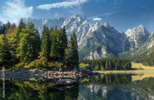 Scenic image of Fairytale lake Fusine during sunset. Picturesque landscape with lake  forest and majestic mount. Wonderful Autumn landscape. Picturesque view of nature. Amazing natural Background