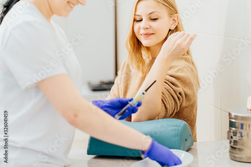 Laboratory nurse takes real blood sample phlebotomist with vacuum capsule for analysis test from patient arm vein in the hospital. Blood test.