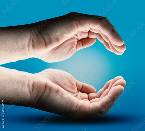 Two Human Hands with Empty Space on Blue Background. Energy - Light and Power Concept. Future Product Presentation.