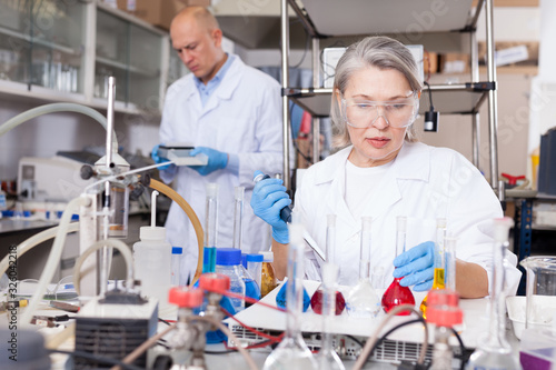 Female biochemists mixing chemicals