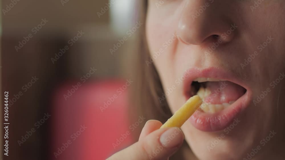 Young woman eating fast food french fries at a McDonalds cafe. Close-up portrait. Young woman eating fast food french fries at a McDonalds cafe. Close-up portrait.