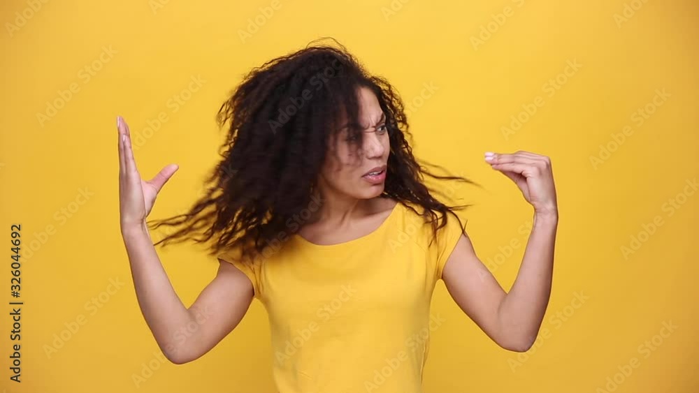 Young african american girl with curly hair in yellow t-shirt posing showing blah blah gesture ja jaja hands isolated on bright orange background in studio. People sincere emotions, lifestyle concept Young african american girl with curly hair in yellow t-shirt posing showing blah blah gesture ja jaja hands isolated on bright orange background in studio. People sincere emotions, lifestyle concept