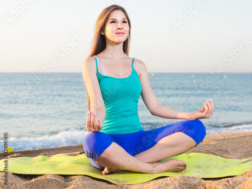 Female 20-25 years old is sitting and practicing meditation in blue T-shirt