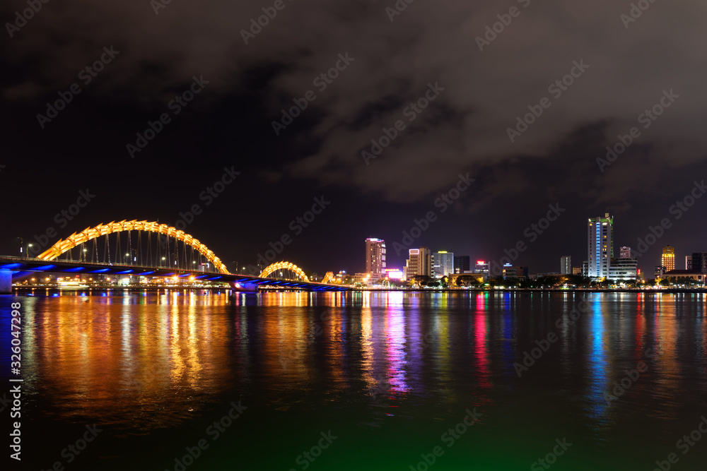 Night scene of Han river, illuminated Dragon bridge and buildings in DaNang city, Vietnam