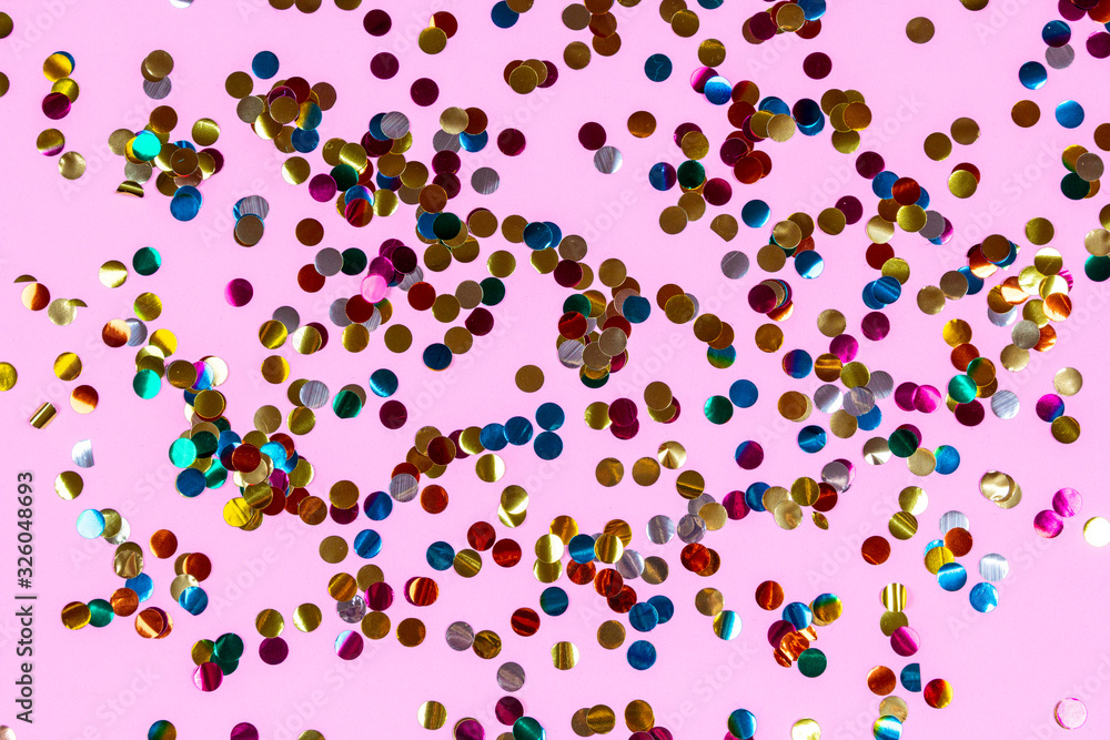 Gold colorful confetti of large size on pink background. Festive backdrop of sparkles for birthday, carnival