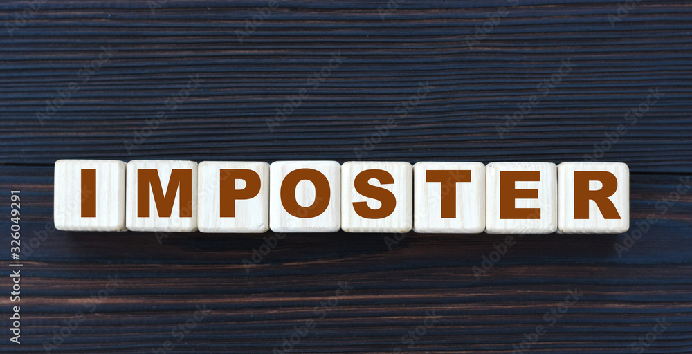 concept word impostor on cubes on a dark wooden background concept word impostor on cubes on a dark wooden background
