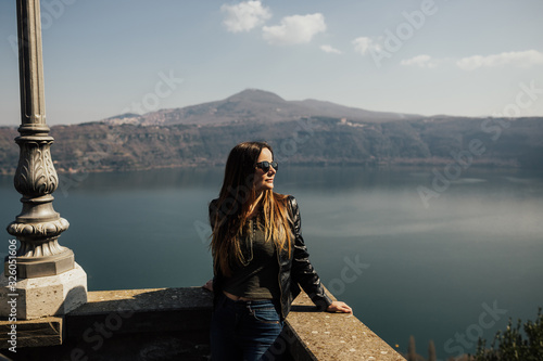 Woman enjoying view of majestic mountain lake. Explore travel, discover beautiful earth. Sunny photo of a sexy girl with lake Albano on background.