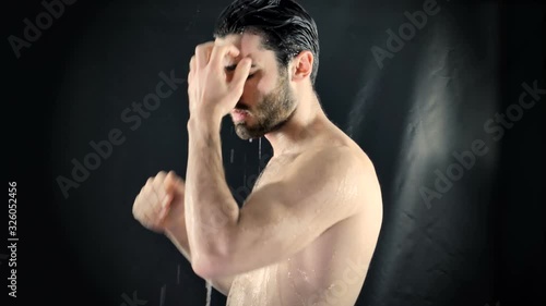 Young Bare Muscular Young Man Receiving Water Splashes in Studio photo