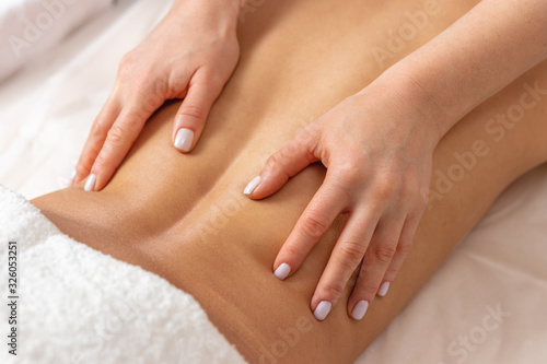 close-up professional masseuse performing with hand back massage to young woman client in wellness spa center, beauty photo concept and atmosphere of calm and relaxation