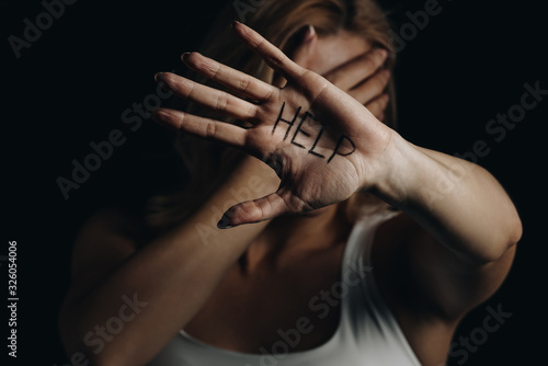 Victim with obscure face showing palm with help lettering isolated on black