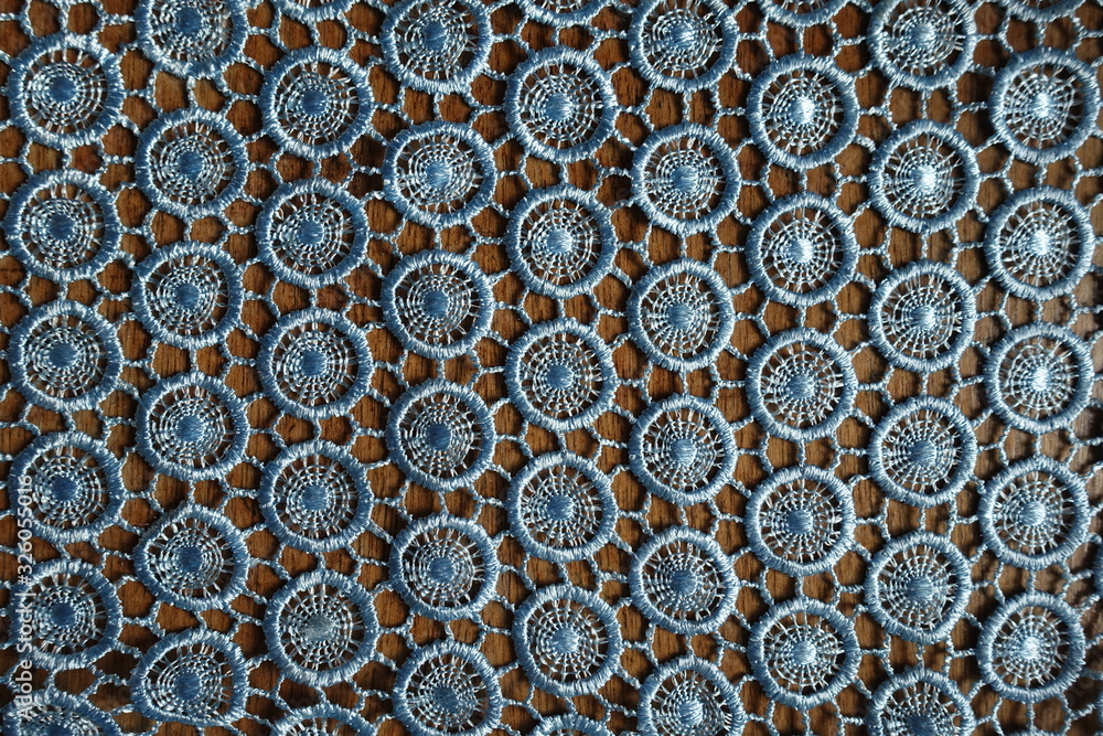 Light blue crochet lacy fabric on wood from above