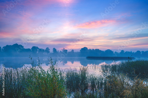 Magic sunrise over the lake. Misty early morning, rural landscape, wilderness, mystical feeling. Serenity lake in magical light photo