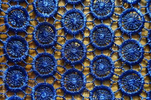 Shiny dark blue crochet lacy fabric on wood from above