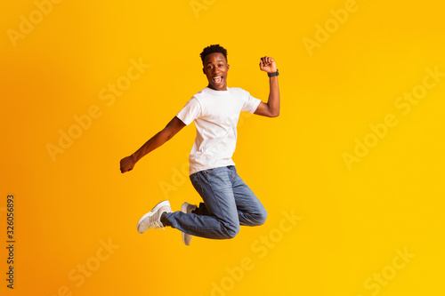 Young african man jumping as crazy, carefree, celebrating victory © Prostock-studio