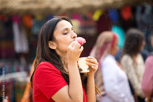 One women eating flavored ice gola dipped in syrup