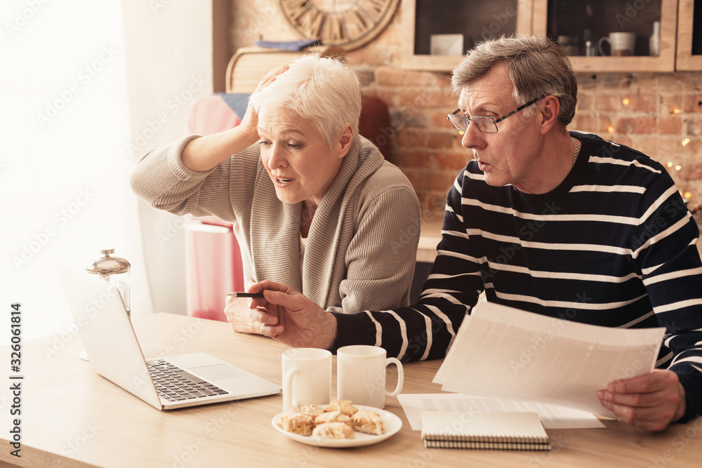 Concerned Senior Couple Using Laptop In Kitchen, Managing Family Budget Concerned Senior Couple Using Laptop In Kitchen, Managing Family Budget
