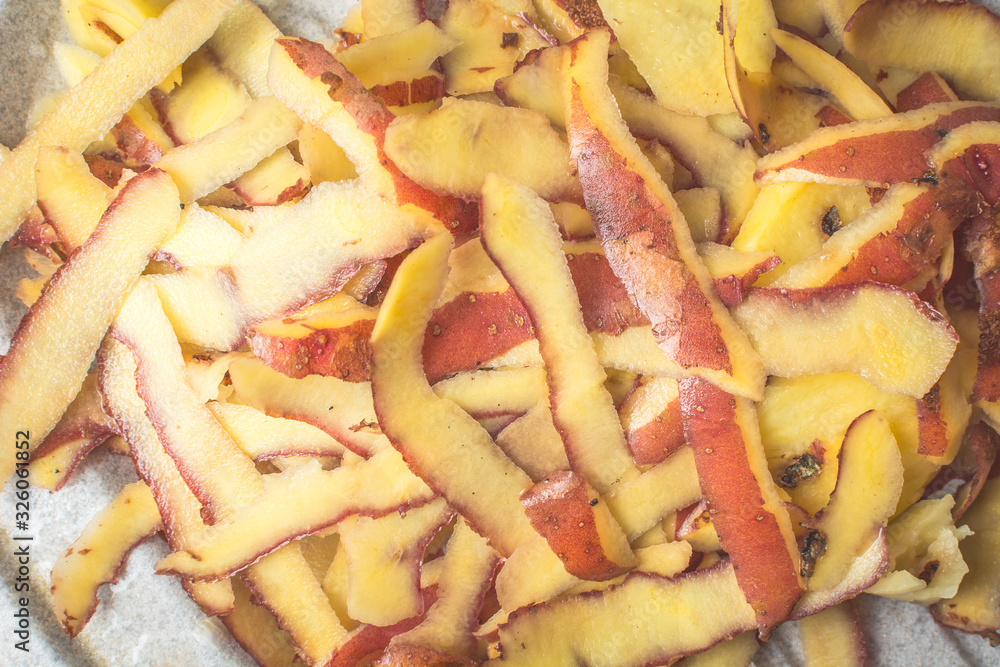 Purified skin of white potatoes with special knife on sink.