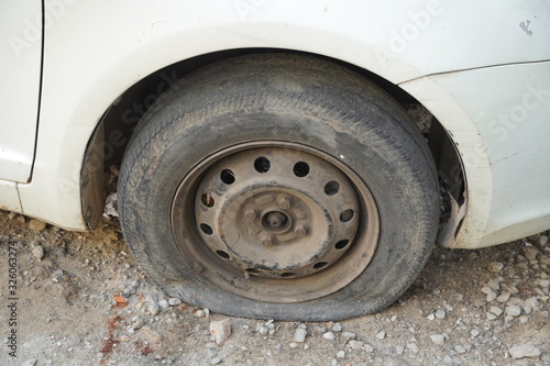 Tire leak, close up wheel of old white vintage car. Car wheel flat tire on the road. Deflated the tyre of an old car next to a motorcycle. - Udaipur India : February 2020