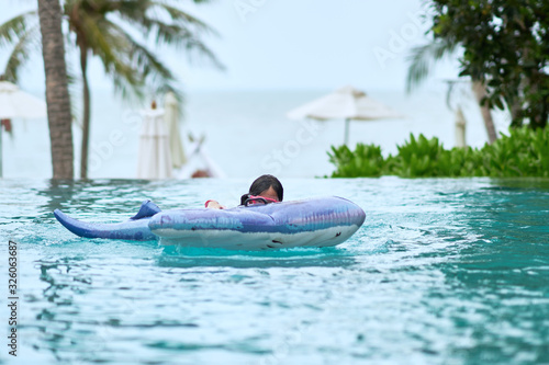 Photography Girl wear goggles on floater in swimming pool with water splash on blur beach ba