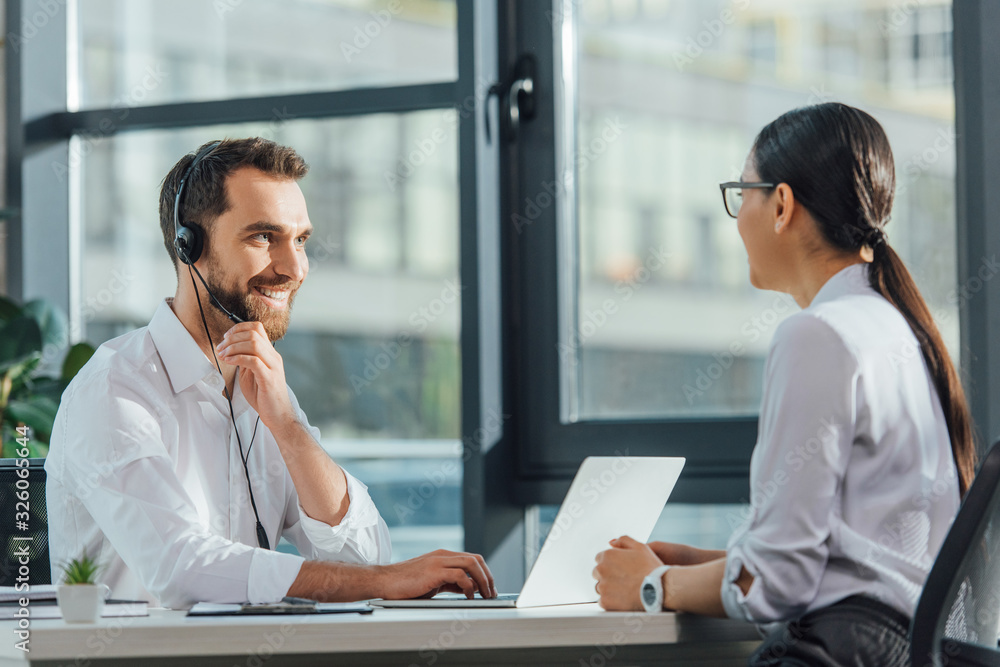 smiling male translator working online with laptop and headset on meeting with businesswoman smiling male translator working online with laptop and headset on meeting with businesswoman
