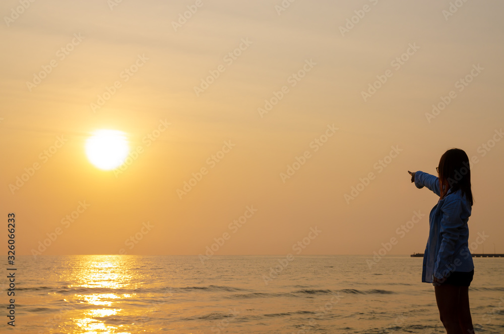 woman stands at the sunset over the sea and the colorful sky.