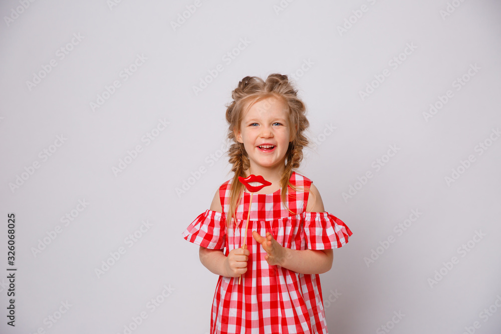 Funny smiling baby girl summer dress on white background . Baby girl with a lip accessory on a stick. Funny smiling baby girl summer dress on white background . Baby girl with a lip accessory on a stick.