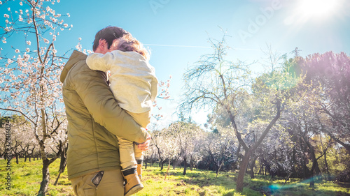 Father and son quality time together in a park with early blooming trees outdoors. Concept of a happy single parent family and lifestyle
