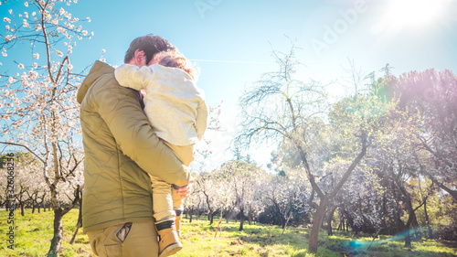 Father and son quality time together in a park with early blooming trees outdoors. Concept of a happy single parent family and lifestyle