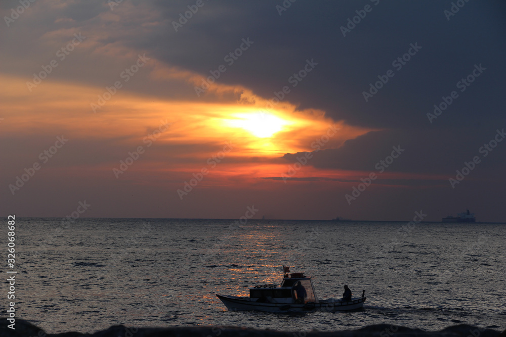 people in a boat on a sea at sunset