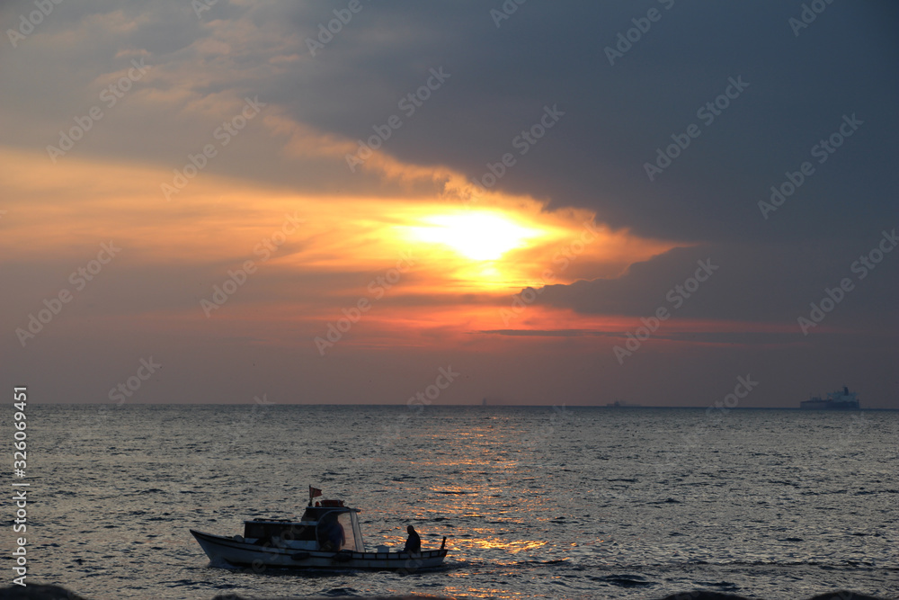 people in a boat on a sea at sunset