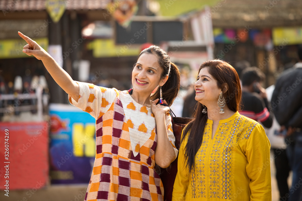 Two happy Indian women shopping at street market