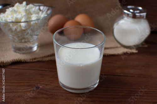 Homemade rustic crumbly cottage cheese with milk on a wooden background. Still-life.