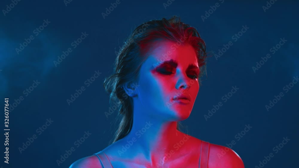 Beauty model with dark makeup expressively looking in camera, portrait in bright contrast neon lighting. Attractive young girl in lingerie emotionally posing in studio, trendy UV light Beauty model with dark makeup expressively looking in camera, portrait in bright contrast neon lighting. Attractive young girl in lingerie emotionally posing in studio, trendy UV light