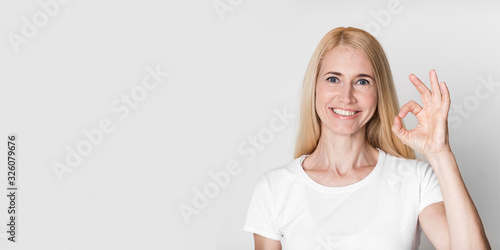 Happy mature woman gesturing okay sign and smiling