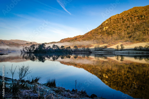 Early morning reflections on the lake at Rydal in the Lake District Cumbria showing the mist hovering over the water. 