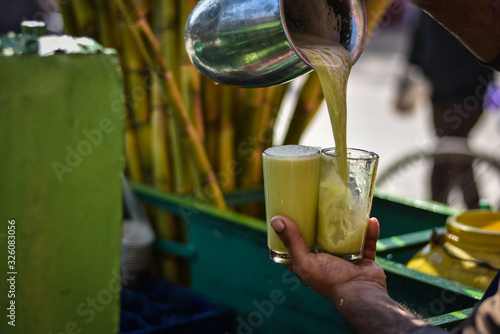 hand holding a glass of Indian sugarcane juice in street market in Haridwar Uttarakhand, Indian Drink 