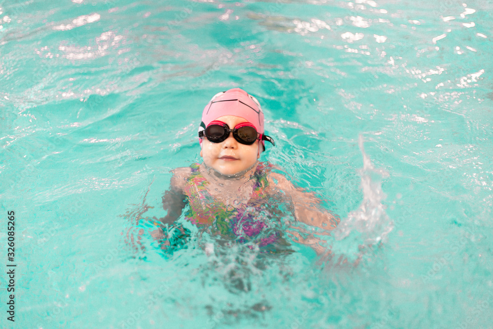 baby girl enjoying swimming in a pool, swimming lesson of young children in the pool, learning to swim in the childrens pool, early childhood development