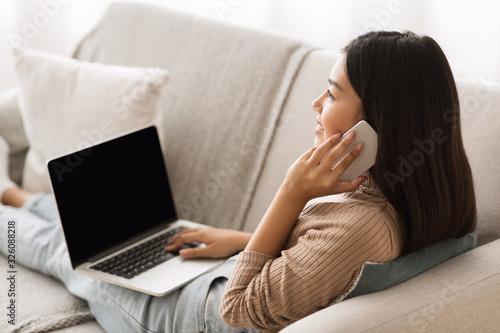 Teen girl multitasking, websurfing on laptop and talking on phone