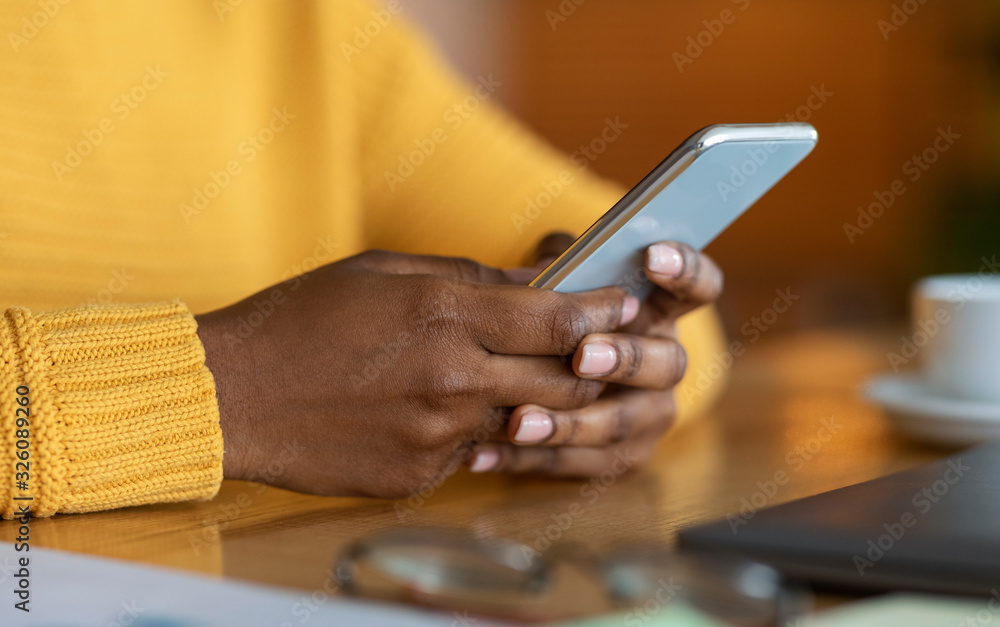 Fototapeta premium Hands of black woman holding modern smartphone