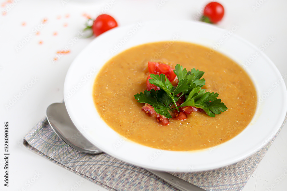 Vegetable soup with lentils on a white background. Served with chopped cherry tomatoes and herbs. Nearby are pieces of ciabatta. Raw groats in the background. Vegetarian dish. Vegetable soup with lentils on a white background. Served with chopped cherry tomatoes and herbs. Nearby are pieces of ciabatta. Raw groats in the background. Vegetarian dish.