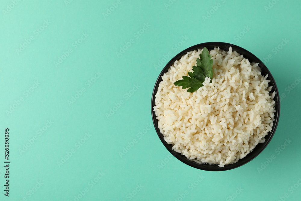 Bowl with boiled rice and parsley on mint background, top view Bowl with boiled rice and parsley on mint background, top view