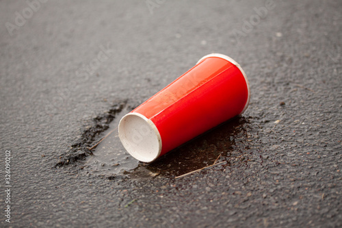 Soda cup thrown on ground on asphalt road. Plastic wast destroying the planet.