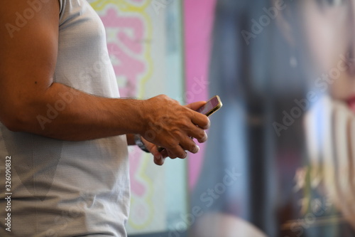 A japanese girl is typing a message on her smartphone in front of a blurred background. A young woman is holding a cell phone in her hands..