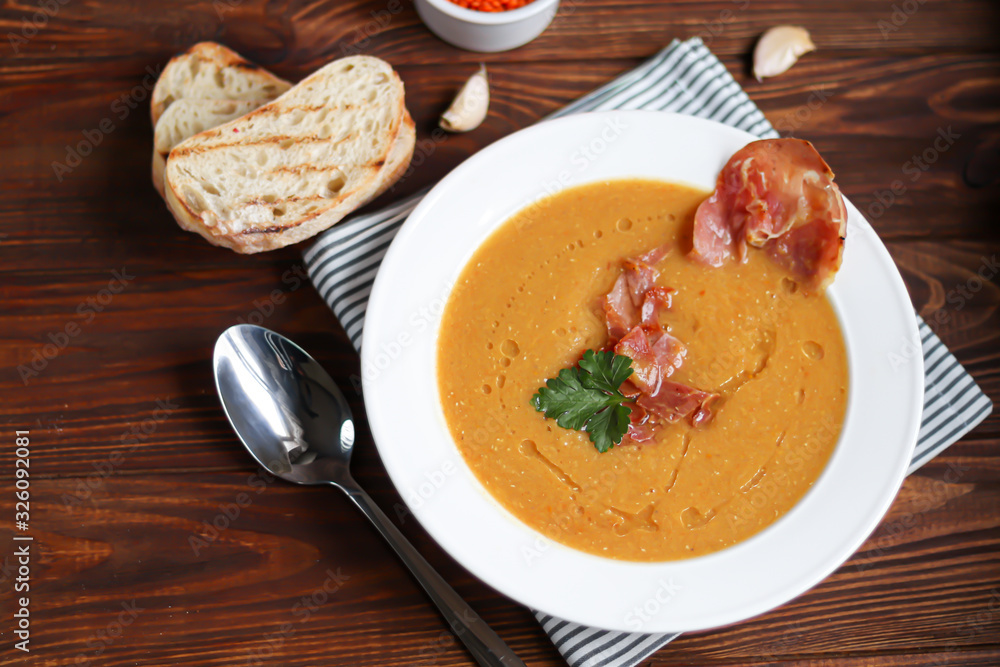 Vegetable soup with lentils on a wooden background. Served with chopped cherry tomatoes and herbs. Nearby are pieces of ciabatta. Raw groats in the background. Vegetarian dish. Vegetable soup with lentils on a wooden background. Served with chopped cherry tomatoes and herbs. Nearby are pieces of ciabatta. Raw groats in the background. Vegetarian dish.