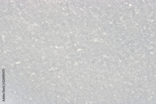 The texture of freshly fallen snow. Christmas template for design. Clearly visible individual snowflakes. Winter background.