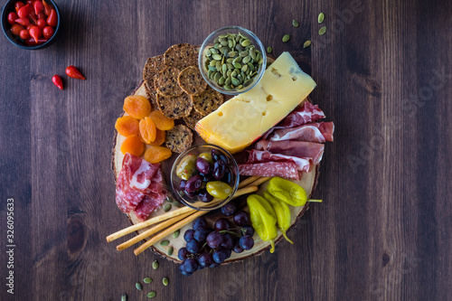 Charcuterie board filled with prosciutto, cheese and various other finger foods. photo