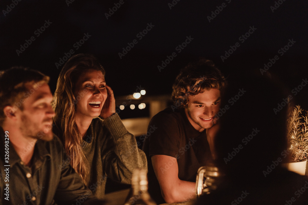 Smiling woman sitting with male friends in restaurant at night Smiling woman sitting with male friends in restaurant at night