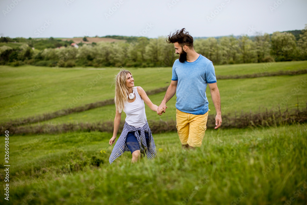Loving couple enjoying a walk through grass land Loving couple enjoying a walk through grass land