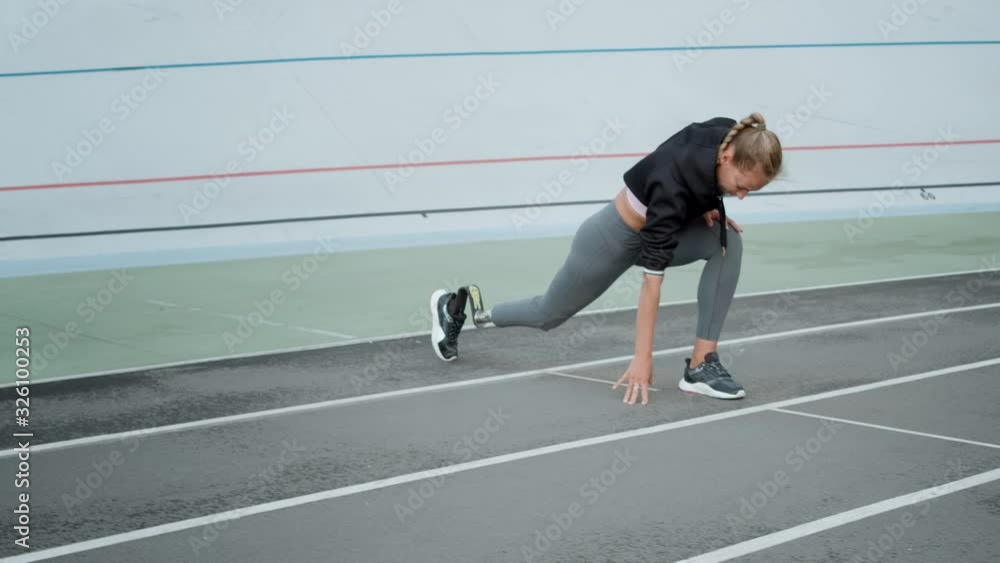 Handicapped fit girl stretching legs at stadium. Athlete warming at stadium Handicapped fit girl stretching legs at stadium. Athlete warming at stadium